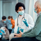 masked doctor talking to masked patient