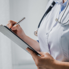 Physician writing on clipboard